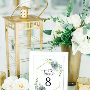 May include: White table number card with a gold hexagonal frame and blue and white floral design. The card says "Table 8".