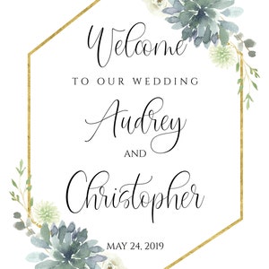May include: A gold hexagonal frame with a watercolor floral design in shades of blue and green. The text inside the frame reads "Welcome to our wedding Audrey and Christopher May 24, 2019".
