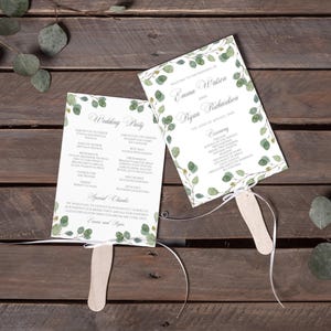Puede incluir: Dos abanicos de programa de boda blancos con mangos de madera y lazos de cinta blanca. Las tarjetas presentan ilustraciones de hojas de eucalipto verdes y texto negro que detalla el cortejo nupcial, el programa de la ceremonia y agradecimientos.