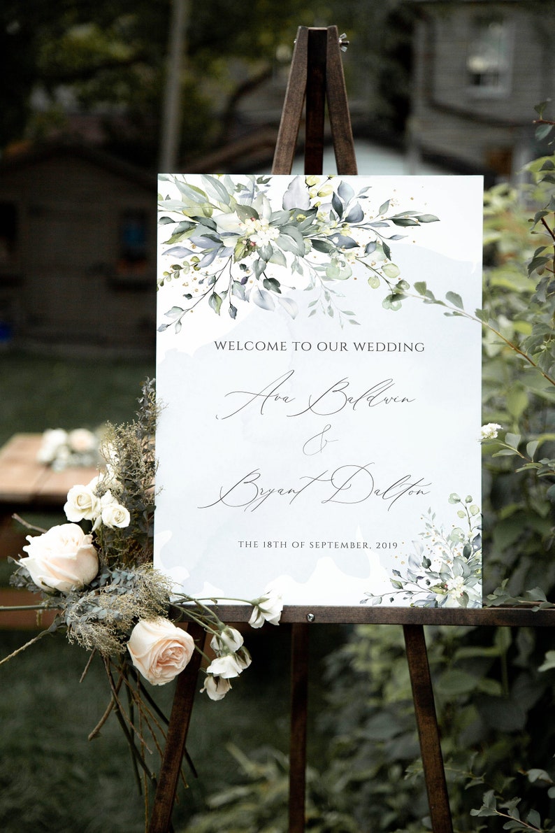 May include: A wedding welcome sign with a watercolor floral design in shades of green and white. The sign reads "Welcome to our wedding, Ava Baldwin & Bryant Dalton, The 18th of September, 2019."