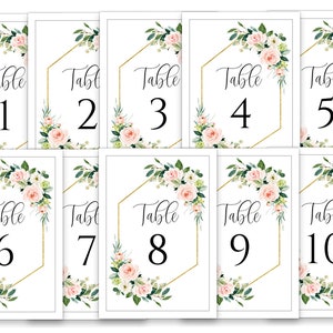 Puede incluir: Diez tarjetas de n&uacute;mero de mesa blancas con marcos hexagonales dorados y dise&ntilde;os florales. Los n&uacute;meros del 1 al 10 est&aacute;n impresos en negro.