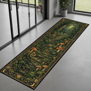 Puede incluir: Una alfombra rectangular con un diseño de sendero forestal y setas. La alfombra tiene un borde negro con detalles dorados y un patrón detallado. La imagen central representa un camino a través de un bosque exuberante con setas de sombrero naranja.