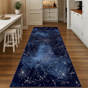 Peut inclure: Un tapis rectangulaire bleu foncé avec un motif céleste. Le tapis présente une carte détaillée des constellations et des étoiles en blanc, avec un effet de dégradé du bleu foncé au bleu plus clair. Le tapis est posé sur un sol en bois.