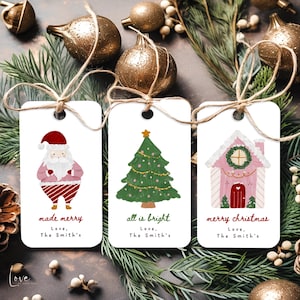 Puede incluir: Tres etiquetas de regalo navideñas blancas con ilustraciones festivas. Una presenta a Papá Noel, otra un árbol de Navidad y la última una casa de jengibre rosa. Cada etiqueta tiene una cuerda de yute y las frases "made merry", "all is bright" y "merry christmas".