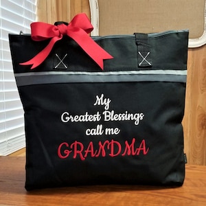 May include: Black zippered tote bag with a red bow. The bag has a gray stripe and the text "My Greatest Blessings call me GRANDMA" embroidered in white.