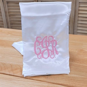 May include: White satin sleep mask with pink embroidered initials "C.S.R."