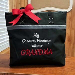 Puede incluir: Bolsa de mano negra con un lazo rojo y el texto "My Greatest Blessings call me GRANDMA" bordado en blanco y rojo.