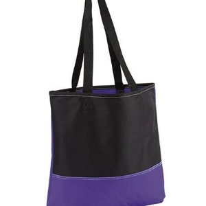 Puede incluir: Una bolsa de mano negra y morada con dos asas negras. La bolsa tiene una secci&oacute;n superior negra y una secci&oacute;n inferior morada.