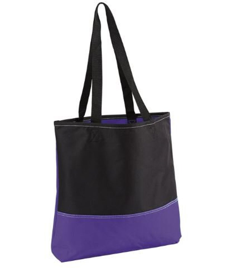 Puede incluir: Una bolsa de mano negra y morada con dos asas negras. La bolsa tiene una secci&oacute;n superior negra y una secci&oacute;n inferior morada.