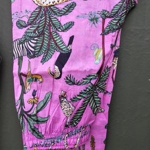 Puede incluir: Pantal&oacute;n de pijama rosa con un estampado de jungla vibrante que presenta un leopardo, una cebra, un tuc&aacute;n y otras aves y follaje tropicales. El pantal&oacute;n tiene un ribete blanco y una cintura el&aacute;stica. La tela es suave y ligera.