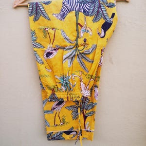 Pu&ograve; includere: Pantaloni da pigiama gialli con stampa a tema giungla. Il design presenta zebre, tucani, fenicotteri e leopardi in mezzo a palme e altro fogliame. I pantaloni hanno un girovita con coulisse e finiture bianche.