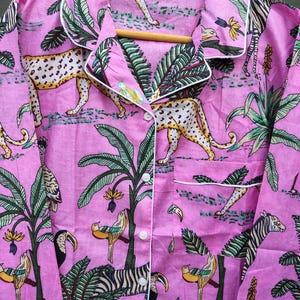 Puede incluir: Camisa de pijama rosa con estampado de tem&aacute;tica selv&aacute;tica. El dise&ntilde;o presenta leopardos, cebras, tucanes y p&aacute;jaros entre palmeras y follaje. La camisa tiene ribetes blancos, cierre de botones y un bolsillo en el pecho.