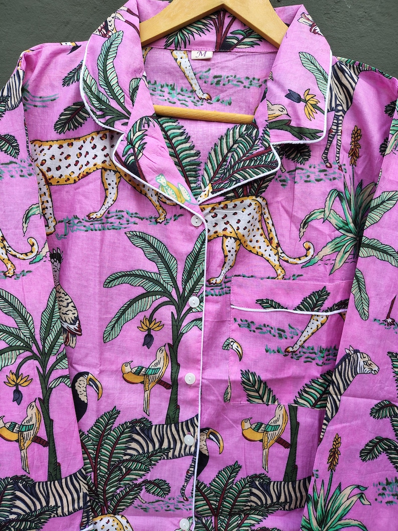 Puede incluir: Camisa de pijama rosa con estampado de tem&aacute;tica selv&aacute;tica. El dise&ntilde;o presenta leopardos, cebras, tucanes y p&aacute;jaros entre palmeras y follaje. La camisa tiene ribetes blancos, cierre de botones y un bolsillo en el pecho.