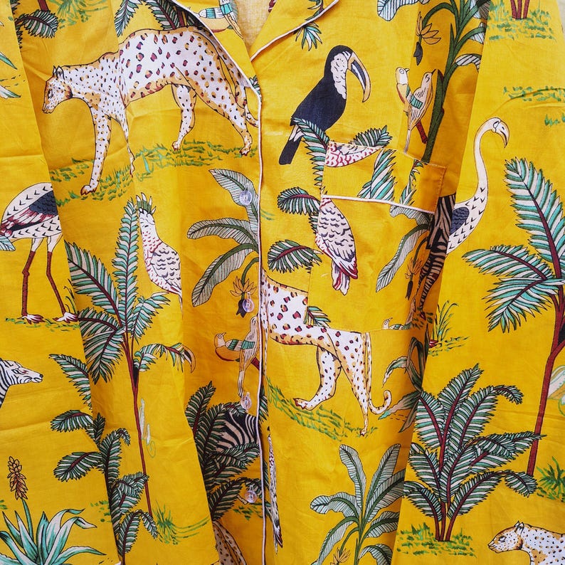 Pu&ograve; includere: Pigiama giallo con una vivace stampa giungla con leopardi, tucani e palme. Il tessuto ha un bordo bianco e un'abbottonatura frontale. Il design include una variet&agrave; di uccelli e animali tropicali.