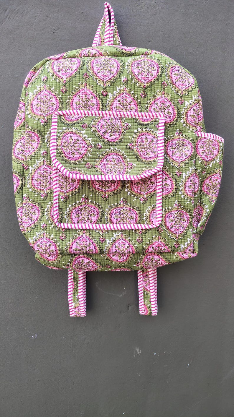 May include: A quilted backpack with a green background and a pink floral pattern. The backpack has a front pocket and pink and white striped trim. The straps and top handle are also pink and white striped.