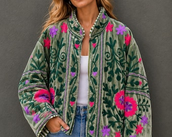 May include: An olive green velvet jacket featuring long sleeves, a high collar, and a front zipper closure. The jacket is decorated with intricate dark green, bright pink, and purple floral embroidery patterns across the front and sleeves.