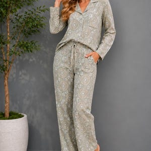 May include: A matching pajama set in a muted green and white mandala pattern. The set includes a button-down shirt with a chest pocket and drawstring pants. The model is wearing the pajama set.