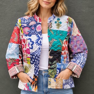 Könnte beinhalten: Bunte Patchwork-Jacke mit floralen, geometrischen und Tiermustern in Rot, Blau, Grün und Lila. Die Jacke hat einen Stehkragen, zwei Taschen und umgeschlagene Ärmel. Sie wird offen mit einer blauen Jeans getragen.