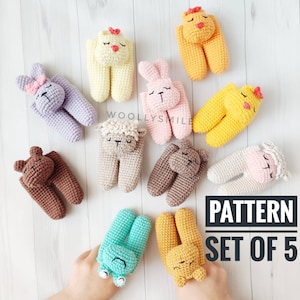 Peut inclure: Un ensemble de 10 jouets en crochet amigurumi en forme d'animaux. Les jouets sont de différentes couleurs, notamment le marron, le rose, le jaune, le vert et le violet. Chaque jouet a un visage d'animal différent, notamment un ours, un lapin, un poussin, un mouton et une grenouille. Les jouets sont tous posés sur une surface en bois blanc. Le texte "PATTERN SET OF 5" est visible dans le coin inférieur droit de l'image.