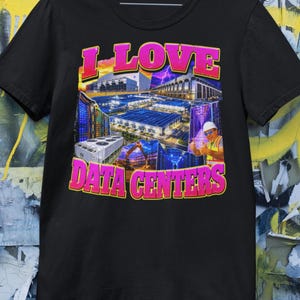 Pode incluir: Uma t-shirt preta de manga curta com uma impressão gráfica com o texto I LOVE DATA CENTERS em cor-de-rosa. O gráfico inclui uma colagem de edifícios de centros de dados, bastidores de servidores, equipamento de refrigeração e uma pessoa.