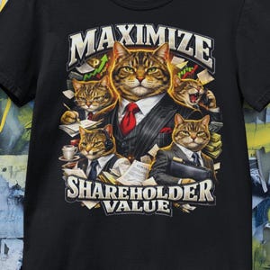 Może przedstawiać: Czarny t-shirt z grafiką przedstawiającą koty w garniturach biznesowych. Obraz zawiera słowa "MAXIMIZE SHAREHOLDER VALUE" w stylizowanej czcionce. Koty otoczone są pieniędzmi i wykresami finansowymi.