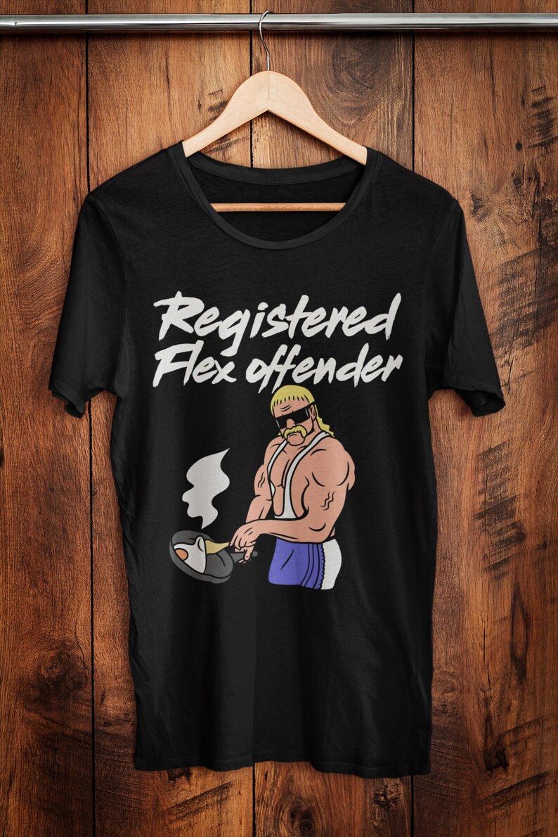 May include: Black t-shirt with the text "Registered Flex Offender" in white script. The shirt features a cartoon illustration of a muscular man with a blonde mullet, sunglasses, and a mustache, cooking in a pan.