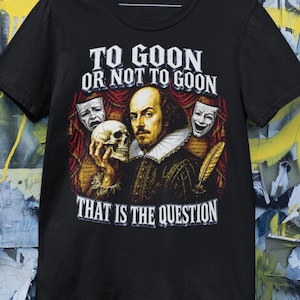 Könnte beinhalten: Ein schwarzes Kurzarm-T-Shirt mit einer Grafik von William Shakespeare, der einen Totenkopf hält. Der Text lautet TO GOON OR NOT TO GOON und THAT IS THE QUESTION. Das Design zeigt rote Vorhänge, zwei Theatermasken und eine goldene Feder.