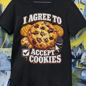 May include: A black short-sleeve t-shirt featuring a graphic print of various cookies, including a large chocolate chip cookie in the center. The text reads "I AGREE TO" above the cookies and "ACCEPT COOKIES" below, with a checkbox and cursor icon.