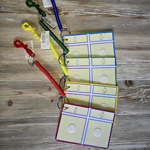 May include: A set of colorful communication boards with matching coiled lanyards. The boards are yellow, green, and blue, with white circles and the words "Now" and "Next". The lanyards are red, yellow, green, and blue.