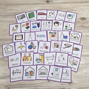 May include: A set of square cards featuring illustrations and text such as "TV," "Books," "Car," and "Lunch." Each card has a white background with a purple border. The cards depict daily activities and routines, suitable for visual aids.