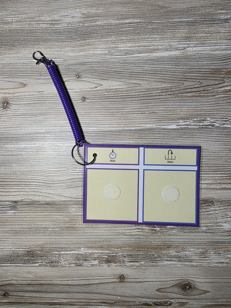 Puede incluir: Un tablero de comunicaci&oacute;n con un borde morado y un cord&oacute;n en espiral morado. El tablero tiene dos secciones con las palabras "Ahora" y "Siguiente" y un recorte circular en cada secci&oacute;n. Un icono de reloj est&aacute; en la secci&oacute;n "Ahora".