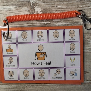 May include: A rectangular communication card set titled How I Feel, featuring twelve illustrated facial expressions labeled Happy, Tired, Excited, Sad, Angry, Proud, Bored, Surprised, Sore, Scared, Calm, Worried, Frustrated, and Ill, attached to an orange coil.