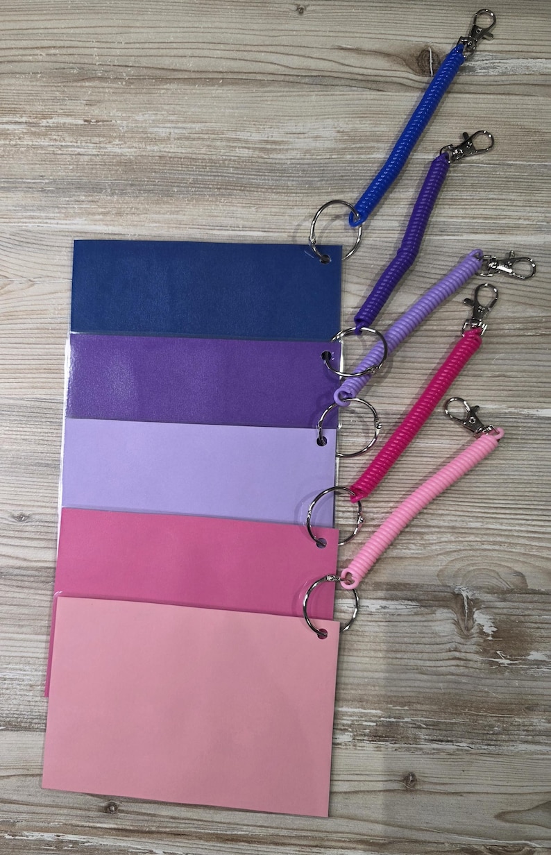May include: A set of five rectangular plastic cards in a gradient of blue, purple, and pink shades, each attached to a matching colored coiled wristband with a metal split ring and a silver-toned lobster clasp for secure attachment.