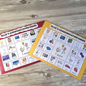 May include: Two rectangular communication boards titled Ollie's Communication Board. Each board features a grid of icons with labels like Drink, Snack, Tablet, Book, Bubbles, Toy, Toilet, Blanket, Sensory Room, Daddy, TV, Puzzle, Music, Car, and Balloon, centered around an I want graphic.