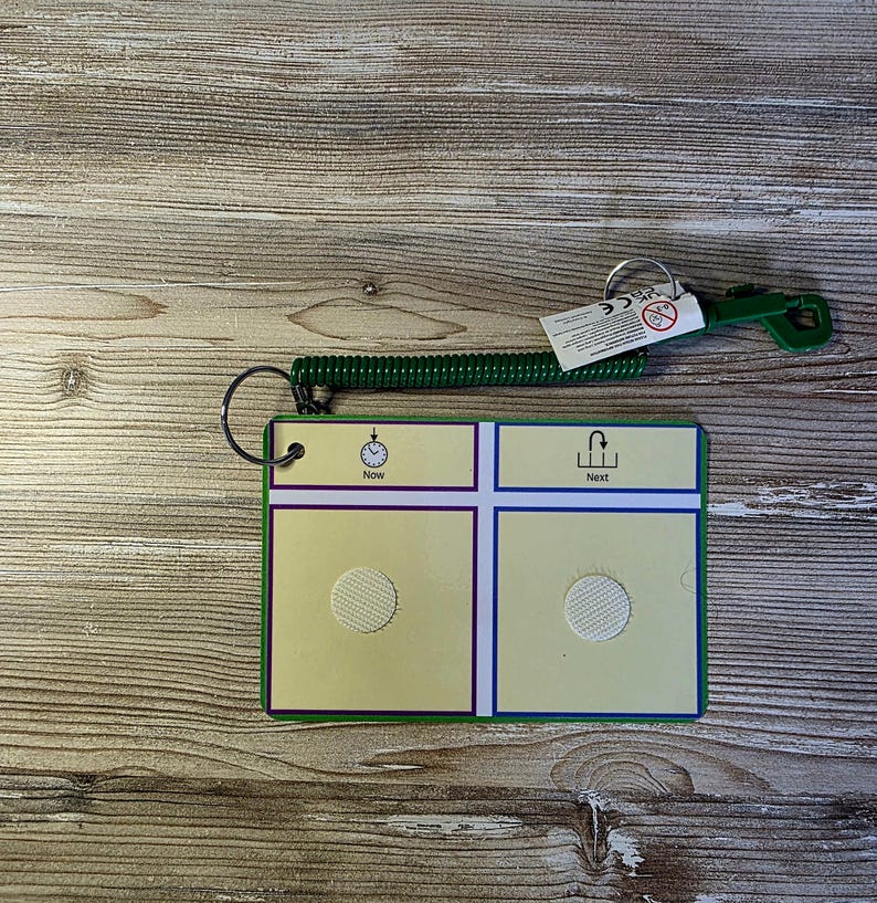 May include: A green and yellow communication board with the words "Now" and "Next". The board has a spiral cord and a green handle. The board has a hook and loop fastener.