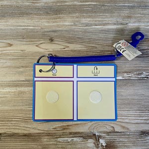 May include: A visual aid card with a blue border and a blue spiral cord. The card has two sections with the words "Now" and "Next". Each section has a white circle. A small tag is attached.