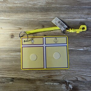 May include: A yellow communication board with a spiral cord and clip. The board has four squares, two with hook-and-loop fasteners. The top of the board has the words "Now" and "Next" with corresponding icons. A tag is attached.