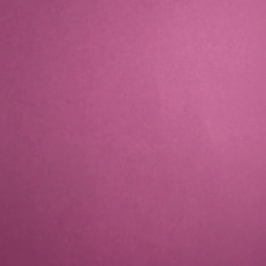 May include: A solid, flat sheet of paper or cardstock with a uniform, matte magenta-pink color. The surface has a subtle, fine-grained texture visible across the entire frame, providing a consistent, monochromatic appearance without any patterns or designs.