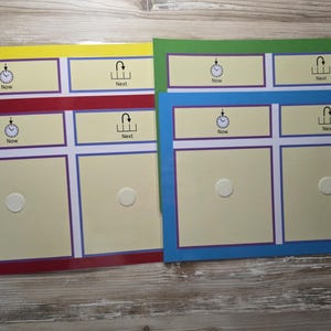 May include: Four colourful visual schedule boards in yellow, green, red, and blue. Each board has sections labelled "Now" and "Next" with clock icons. A white circular fastener is in the centre of each board.