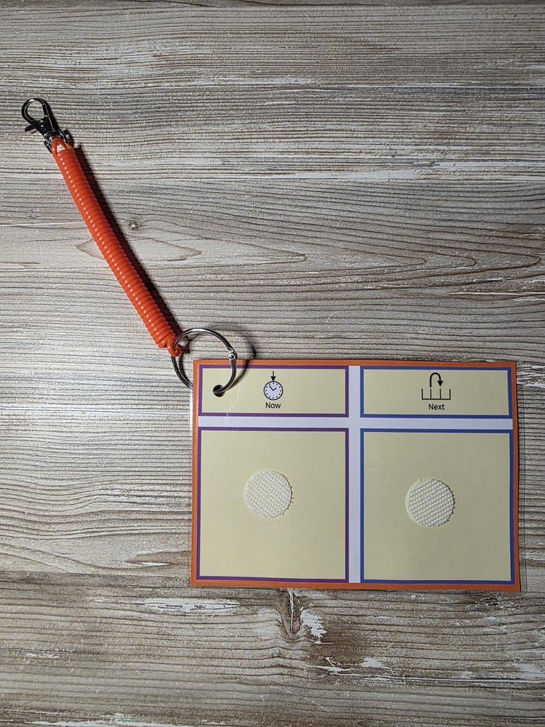 Puede incluir: Una tarjeta de programaci&oacute;n visual con un cord&oacute;n en espiral naranja y un clip met&aacute;lico. La tarjeta tiene un fondo amarillo claro con bordes morados y azules. La tarjeta est&aacute; etiquetada como "Ahora" y "Siguiente" con iconos correspondientes.