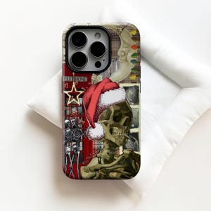 Könnte beinhalten: Handyhülle mit Collage-Design. Sie zeigt einen Totenkopf mit Weihnachtsmütze, eine rote Telefonzelle, Skelette und einen Mond. Die Hülle hat eine glänzende Oberfläche und eine Mischung aus festlichen und gotischen Bildern.
