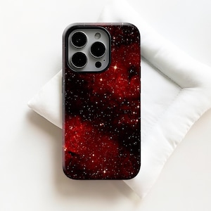 Puede incluir: Una funda de teléfono con un diseño de galaxia rojo oscuro. La funda tiene un borde negro y un recorte para la cámara. El diseño incluye estrellas blancas y nebulosas, creando una estética cósmica. La funda probablemente está hecha de un material duro y protector.