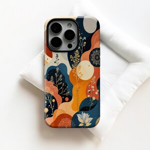 May include: A phone case with a vibrant abstract design. The case displays a pattern of organic shapes in orange, blue, and beige, with floral and mandala-style details. The case has a glossy finish and a camera cutout.