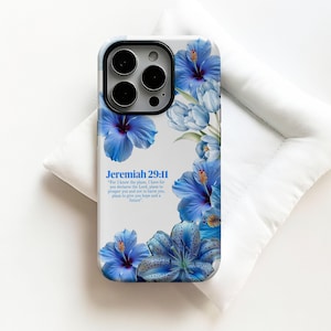 Puede incluir: Una funda de teléfono con un diseño floral con hibiscos azules y otras flores. La funda tiene el texto "Jeremías 29:11" y una cita. La funda está sobre un fondo blanco.
