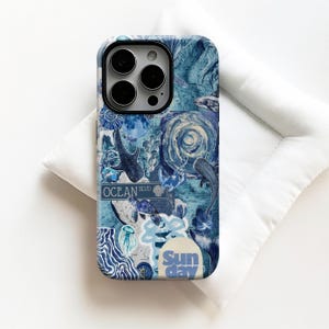 May include: A blue phone case with an ocean-themed collage design. The case features images of sharks, jellyfish, and a street sign that reads "Ocean Blvd." The words "Sun day" are also visible. The case is resting on a white surface.