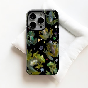 May include: A black phone case featuring a pattern of green and yellow frogs with colorful star accents. The case has a glossy finish and a camera cutout. The frogs are in various poses, creating a playful and whimsical design.
