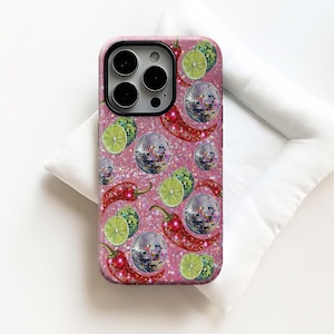 May include: A pink glitter phone case featuring a pattern of red chili peppers, disco balls, and lime slices. The case has a black camera cutout and a glossy finish. The design is fun and vibrant.