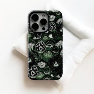 May include: A phone case with a dark green background and a repeating pattern of stylized eyes in black and white. The case has a black border and a camera cutout.