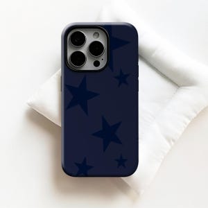 May include: A navy blue phone case featuring a pattern of dark blue stars. The case has a glossy finish and a camera cutout. The phone case is resting on a white surface.