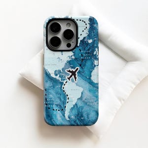 May include: A smartphone case featuring a blue and white world map design. A black airplane graphic marks a dotted flight path. The case has a glossy finish and a camera cutout.